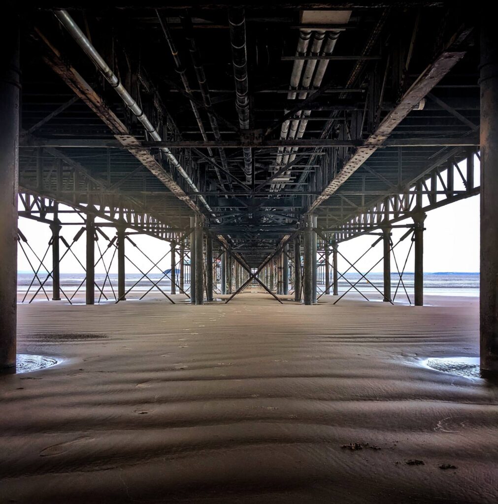 A dark view from beneath Weston-super-Mare pier, showing a cross section of structural steelwork.