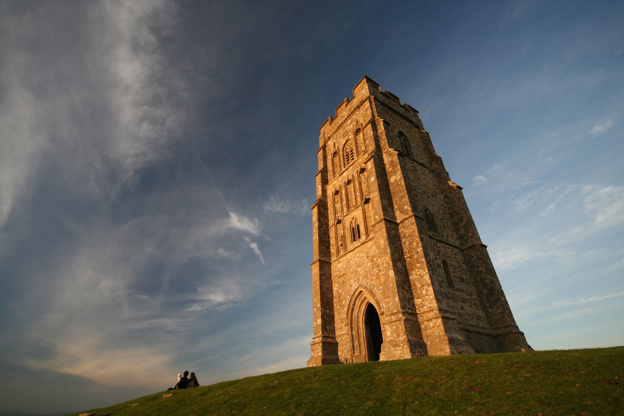 A stone tower on a hill is bathed in golden sunlight.